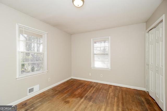 unfurnished bedroom with dark wood-type flooring and a closet