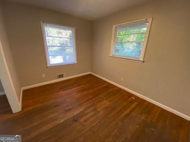 empty room featuring a healthy amount of sunlight and dark hardwood / wood-style flooring