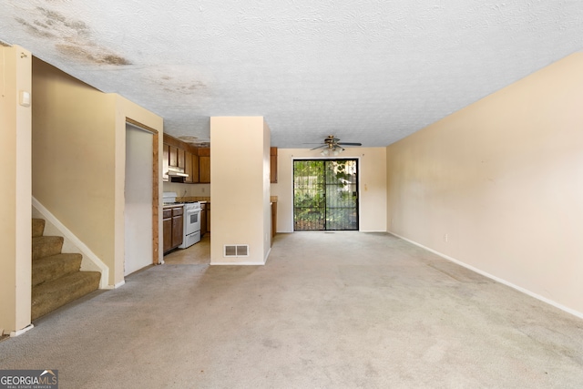 unfurnished living room with ceiling fan, a textured ceiling, and light colored carpet