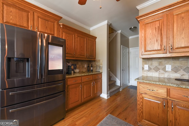 kitchen with decorative backsplash, stainless steel fridge, light stone countertops, and hardwood / wood-style flooring