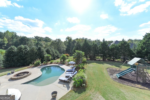 view of swimming pool featuring a lawn, a patio area, and a playground