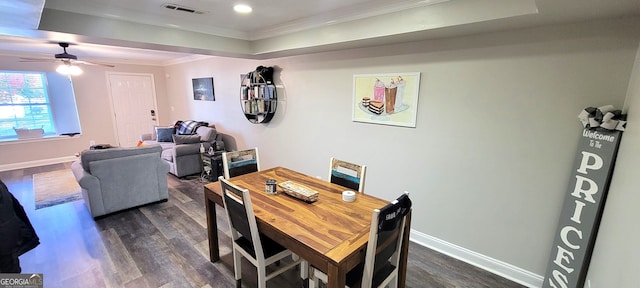 dining space with ceiling fan, a raised ceiling, ornamental molding, and dark hardwood / wood-style floors