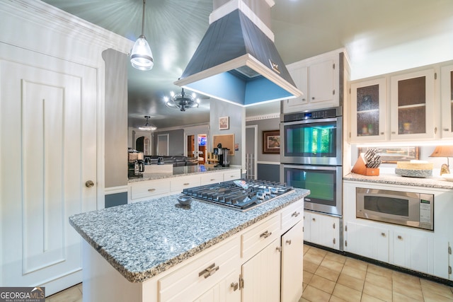 kitchen with appliances with stainless steel finishes, a center island, hanging light fixtures, white cabinetry, and light stone counters