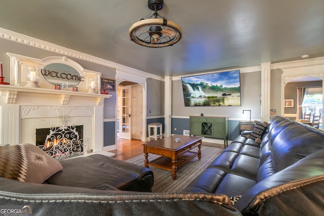 living room with crown molding, wood-type flooring, and a fireplace