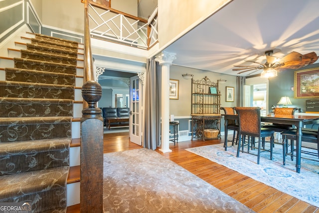 dining space with hardwood / wood-style flooring, ceiling fan, a high ceiling, and decorative columns