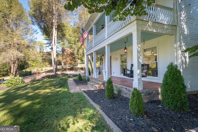 entrance to property with a balcony, covered porch, and a yard