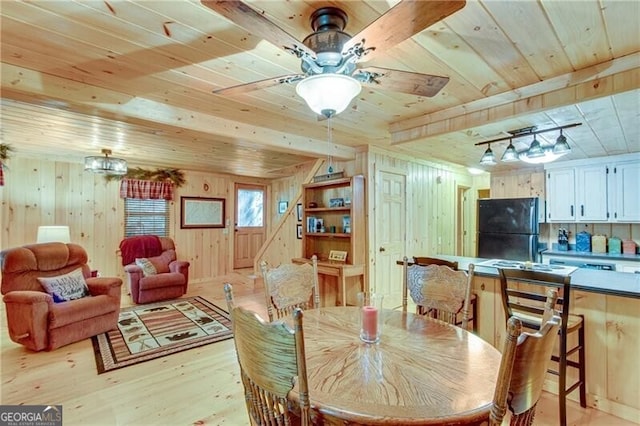 dining area with beam ceiling, wood ceiling, light hardwood / wood-style floors, and wood walls