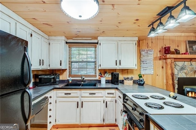 kitchen with white cabinets, hanging light fixtures, sink, and black refrigerator