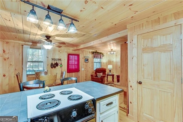 kitchen with wood walls, white range oven, tile counters, and hanging light fixtures