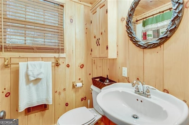 bathroom featuring toilet, wood walls, sink, and a shower with curtain