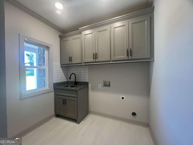 laundry room with electric dryer hookup, light hardwood / wood-style flooring, hookup for a washing machine, ornamental molding, and cabinets