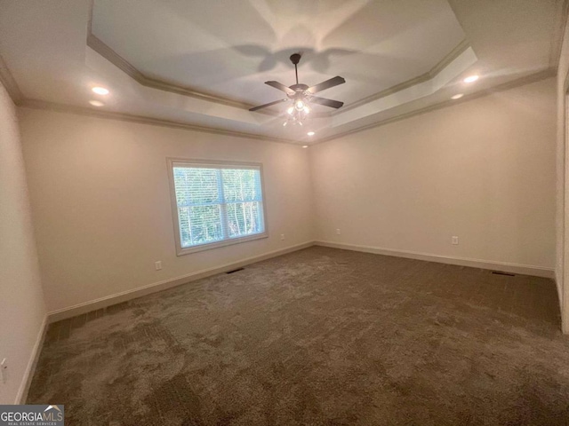 empty room featuring crown molding, dark colored carpet, a tray ceiling, and ceiling fan