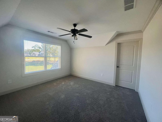 spare room featuring vaulted ceiling, dark colored carpet, and ceiling fan