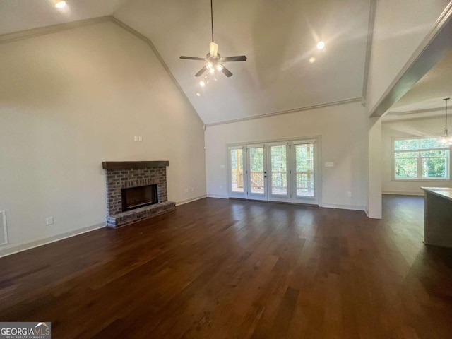 unfurnished living room featuring a wealth of natural light, a brick fireplace, high vaulted ceiling, and dark hardwood / wood-style flooring