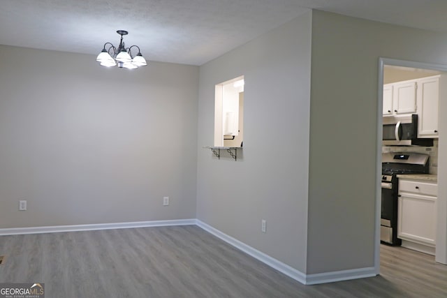 unfurnished dining area with light hardwood / wood-style floors and a notable chandelier