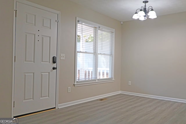 entrance foyer with light hardwood / wood-style flooring and an inviting chandelier