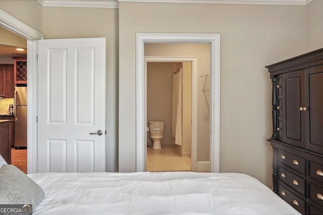 bedroom featuring ensuite bathroom, stainless steel refrigerator, ornamental molding, and tile patterned flooring