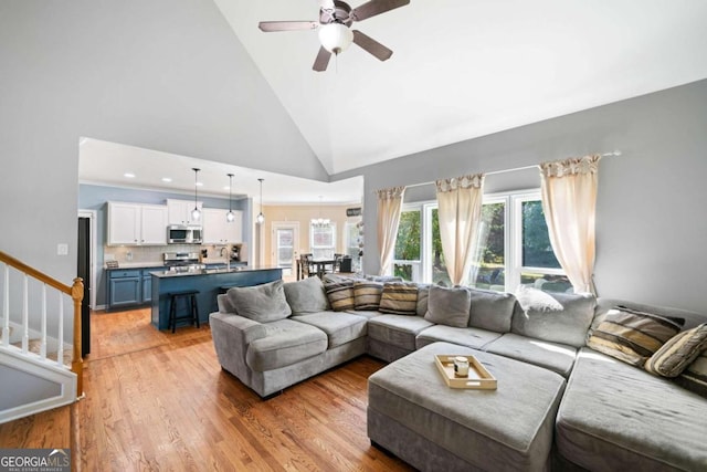 living room featuring light hardwood / wood-style floors, high vaulted ceiling, and ceiling fan with notable chandelier