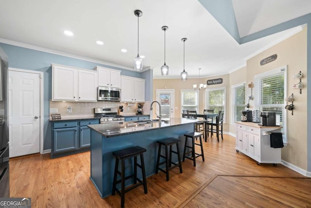 kitchen featuring light wood-type flooring, white cabinetry, stainless steel appliances, a breakfast bar area, and a center island with sink