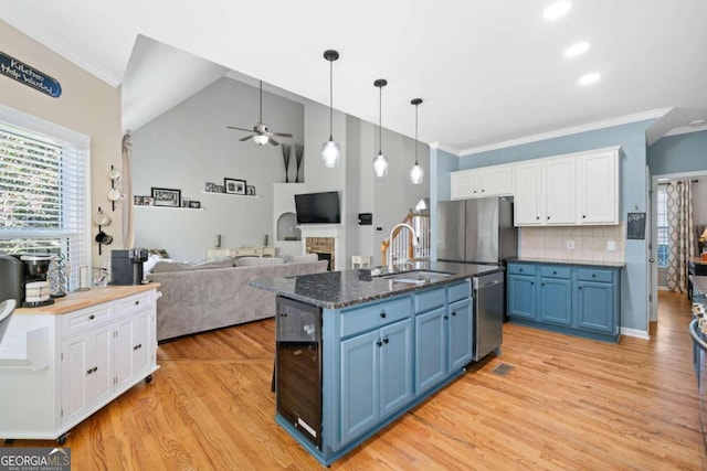 kitchen featuring sink, a stone fireplace, stainless steel appliances, white cabinets, and blue cabinetry