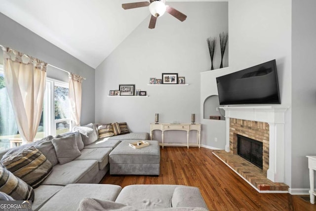 living room with ceiling fan, high vaulted ceiling, dark wood-type flooring, and a brick fireplace