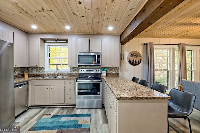 kitchen featuring light hardwood / wood-style floors, stainless steel appliances, a kitchen bar, and white cabinets