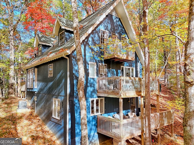 rear view of property featuring central AC, a deck, and a balcony