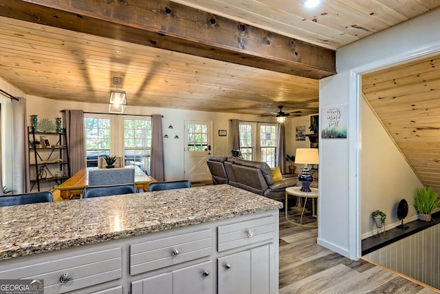 kitchen featuring white cabinets, a healthy amount of sunlight, light stone countertops, and light wood-type flooring