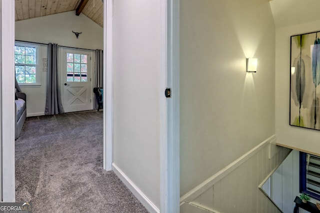 hall with lofted ceiling with beams, wooden ceiling, and light colored carpet