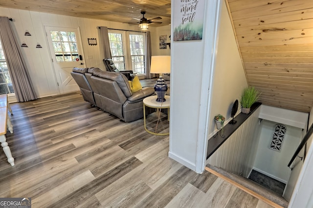 living room featuring hardwood / wood-style floors, wood ceiling, wooden walls, and ceiling fan