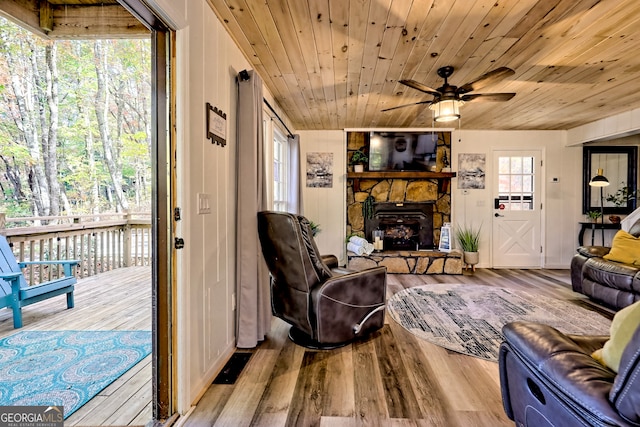 living room with light hardwood / wood-style floors, wood ceiling, a fireplace, and ceiling fan