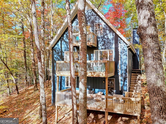 rear view of property featuring outdoor lounge area, a deck, and a balcony