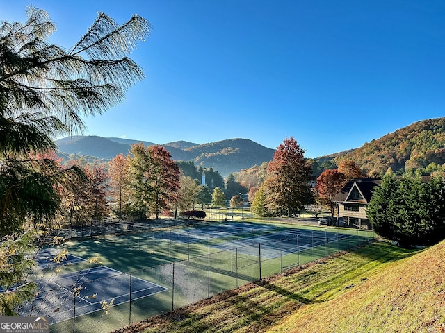 view of sport court with a mountain view and a lawn