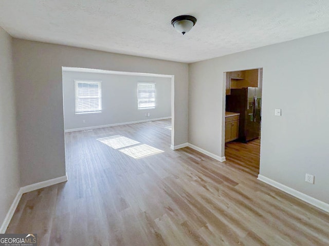 empty room featuring a textured ceiling and light wood-type flooring