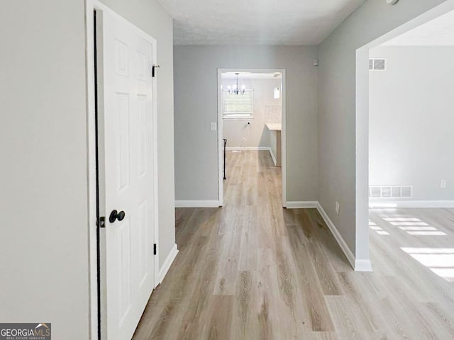 corridor featuring light hardwood / wood-style floors and a chandelier