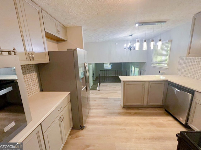 kitchen with kitchen peninsula, appliances with stainless steel finishes, a textured ceiling, light hardwood / wood-style flooring, and pendant lighting