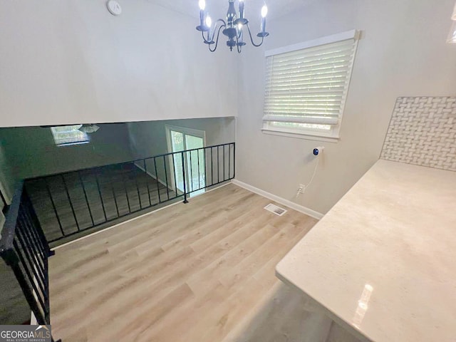 stairway featuring a notable chandelier and wood-type flooring