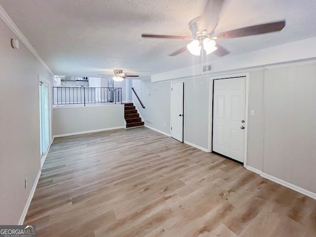 unfurnished room featuring a textured ceiling, ornamental molding, and light hardwood / wood-style flooring