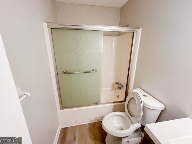 full bathroom featuring toilet, vanity, wood-type flooring, and shower / bath combination with glass door