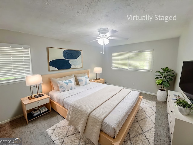 bedroom featuring a textured ceiling, light colored carpet, and ceiling fan