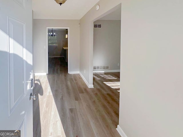 corridor featuring a chandelier and light hardwood / wood-style floors