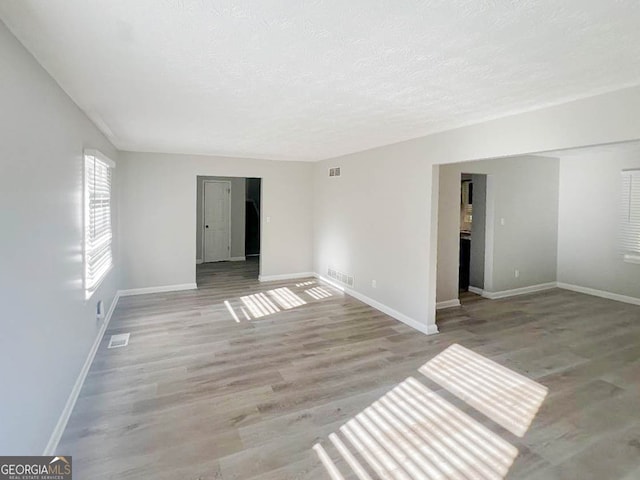 unfurnished room with a textured ceiling and light wood-type flooring