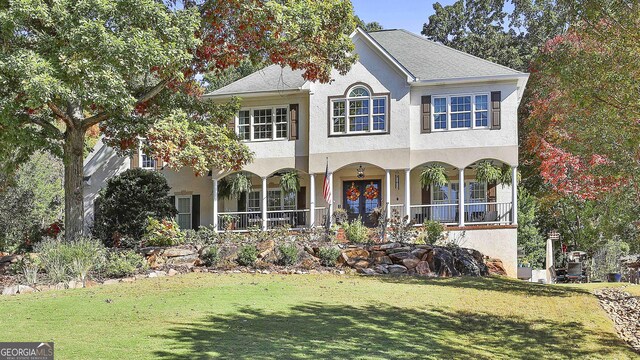 view of front of property featuring a porch, french doors, and a front lawn