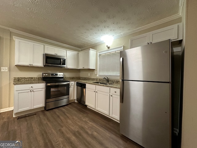 kitchen with white cabinetry, appliances with stainless steel finishes, ornamental molding, and dark hardwood / wood-style floors