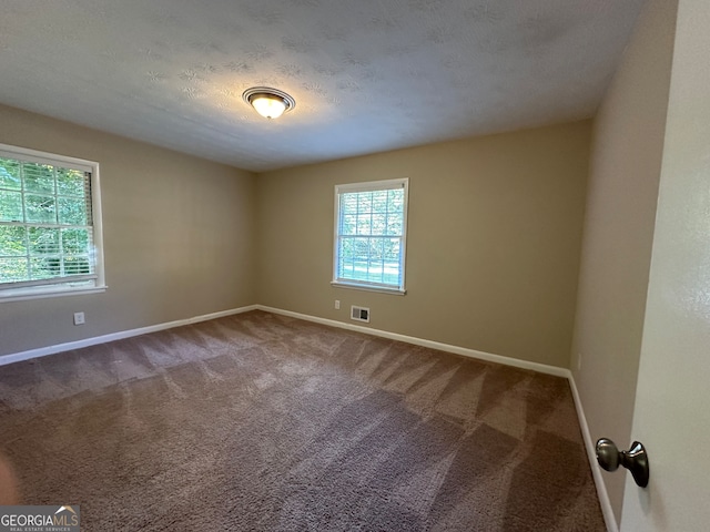 carpeted spare room featuring a textured ceiling