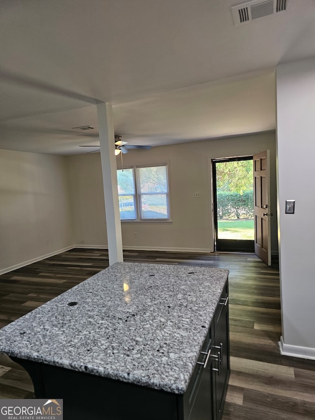 kitchen with a kitchen island, light stone counters, dark hardwood / wood-style floors, and ceiling fan