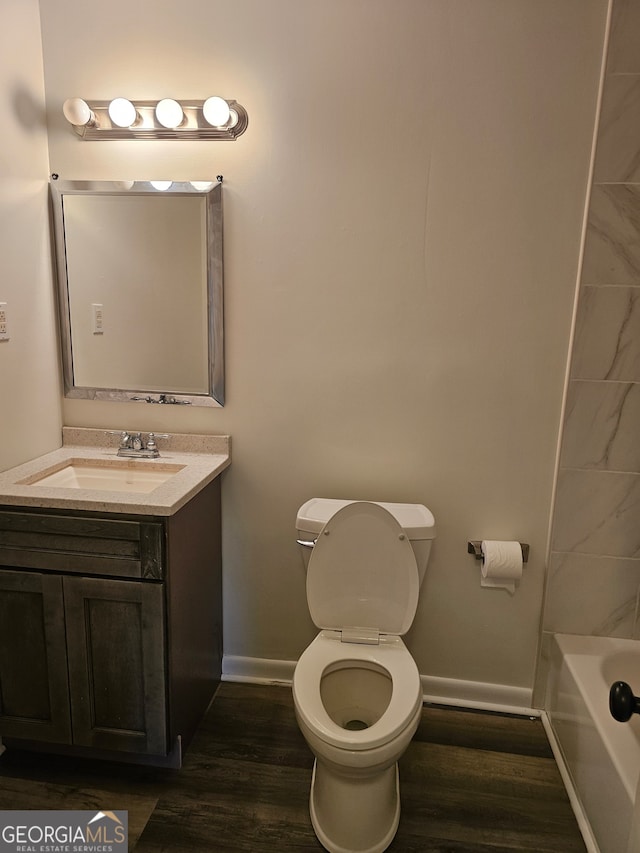 full bathroom with tiled shower / bath, vanity, hardwood / wood-style flooring, and toilet