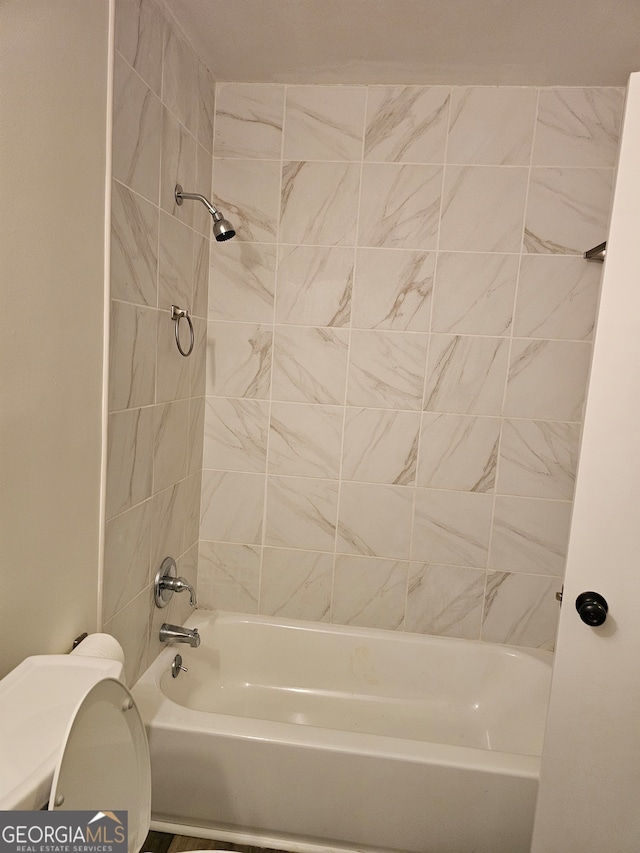 bathroom featuring toilet and tiled shower / bath