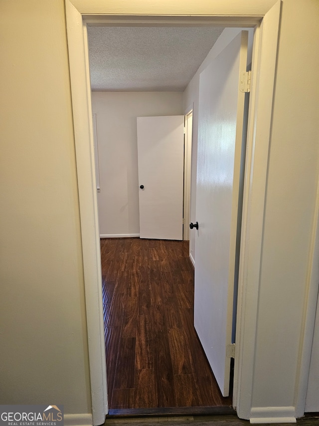 hall with a textured ceiling and dark hardwood / wood-style flooring