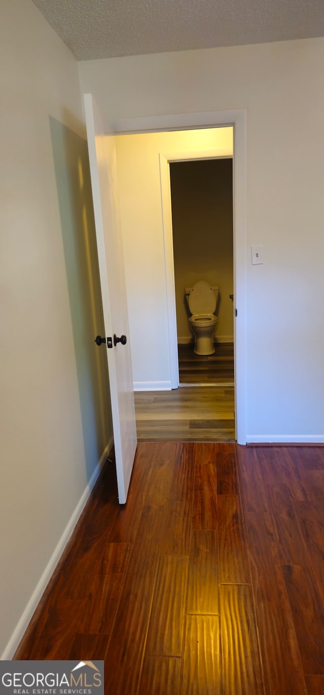 hallway with a textured ceiling and dark hardwood / wood-style floors